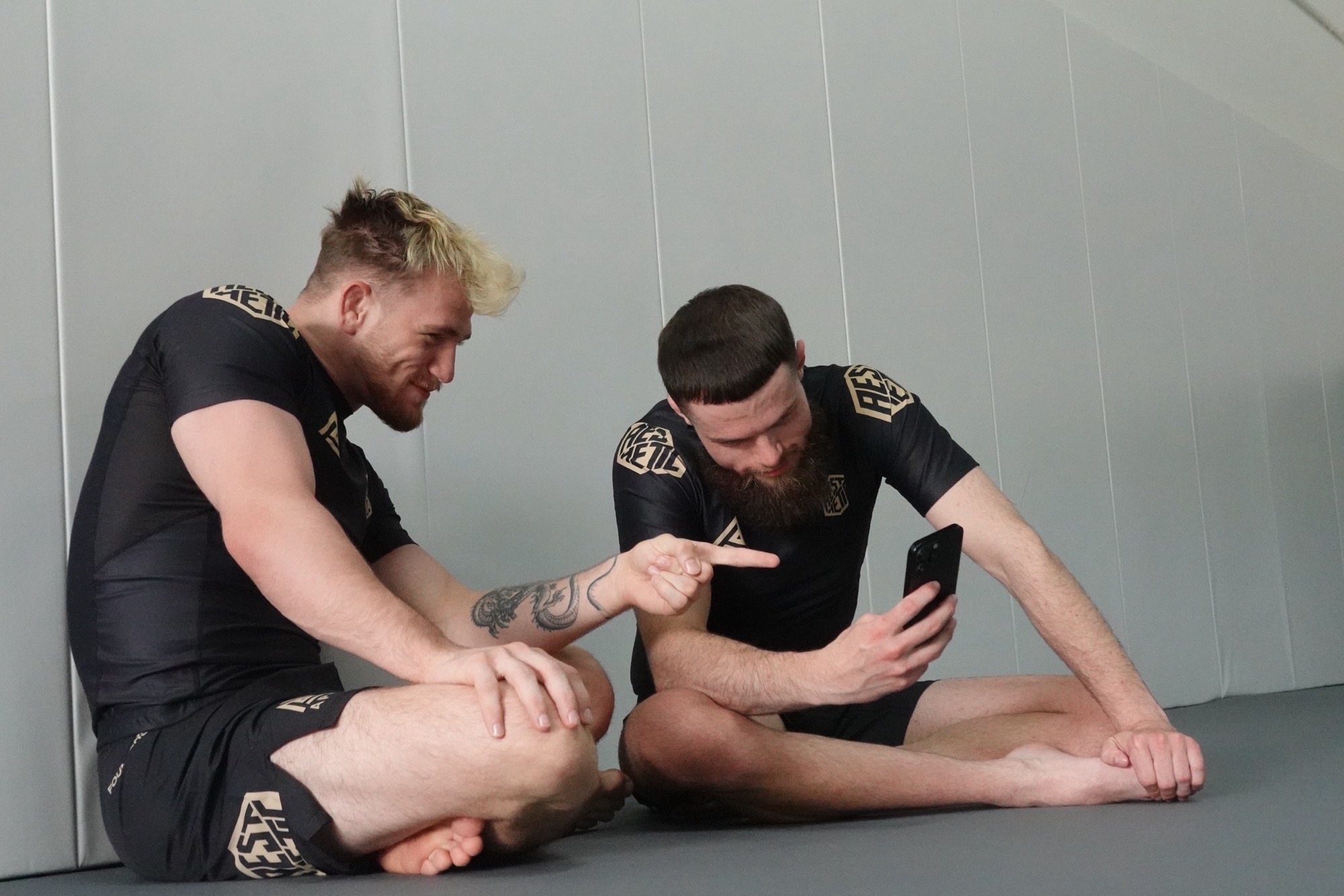 Owen and Elliot on the mat at Apex Jiu-Jitsu Atlanta, reviewing footage between rounds.